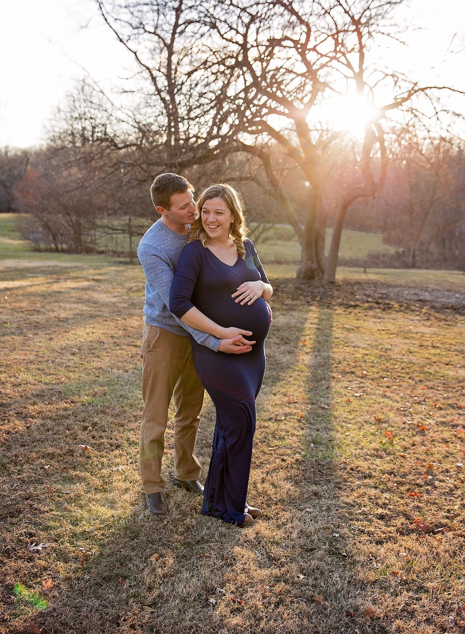 Momma in maternity dress with her husband whispering in her ear.