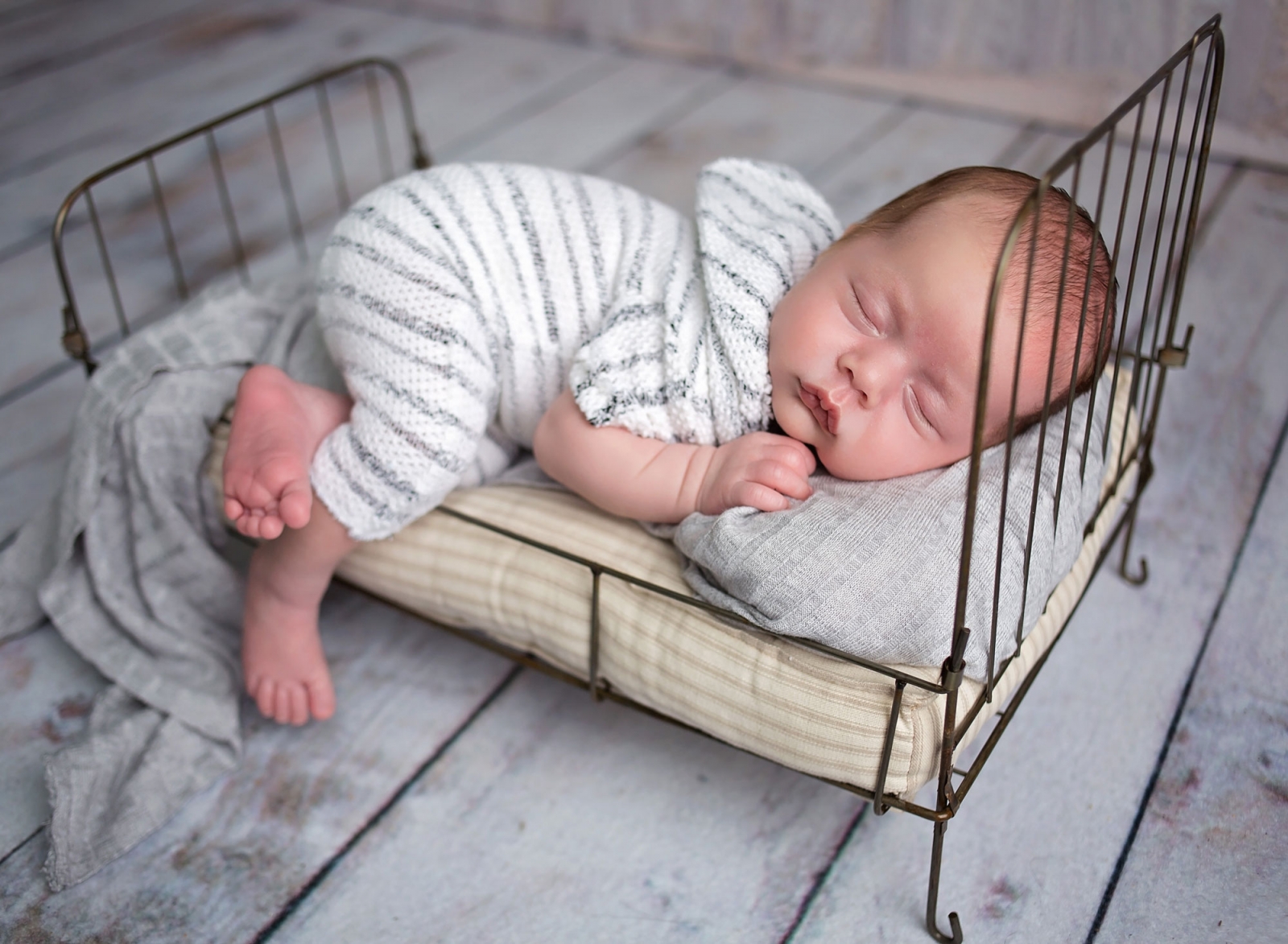 Baby boy with striped nightgown in vintage bed in Orland Park, IL